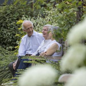 Elderly people sitting on a bench in the gardne